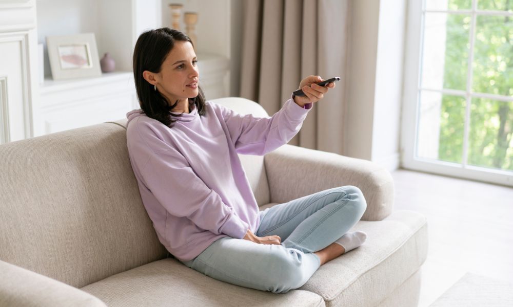 Frau auf Sofa mit Fernbedienung