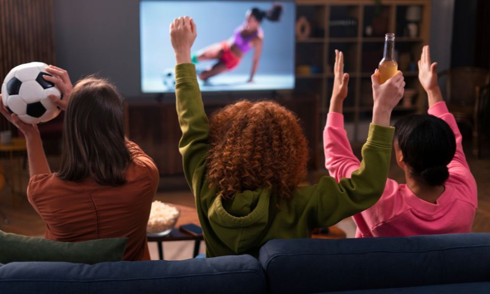 drei Frauen mit Fußball vor Fernseher