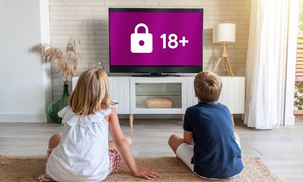 Zwei Kinder sitzen vor dem Fernseher und sehen einen Screen, der gesperrt ist für unter 18jährige